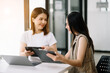 © Nuttapong punna - Two business workers talking on the smartphone and using laptop at the office..