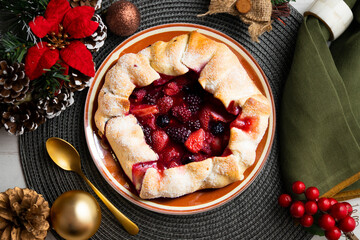 Poster - Red fruit galette with blackberries, strawberries, raspberries. Traditional French recipe. Christmas food served on a table decorated with Christmas motifs.