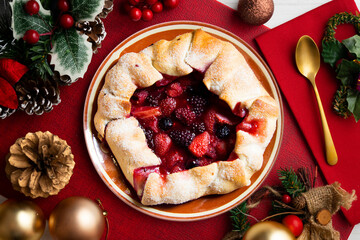 Poster - Red fruit galette with blackberries, strawberries, raspberries. Traditional French recipe. Christmas food served on a table decorated with Christmas motifs.