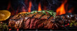 Grilled Steak with herbs cooking over flaming grill