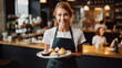 © Santy Hong - Female barista serving coffee and cake on a tray.