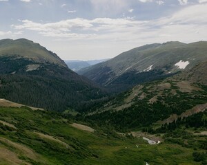 Wall Mural - Scenic view of a green landscape of mountains on a cloudy day