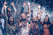 © gstockstudio - Smiling young people dancing and throwing confetti while celebrating New Year in night club together