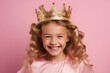 A little smiling girl with a crown on her head at a princess party on a pink background.