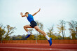 Dynamic steps leading to an impactful long jump. Bottom view full length portrait of professional sportsman running on sport field.
