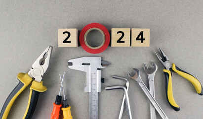 2024 on gray background with various tools. Wooden cubes with numbers 2024 on a gray background