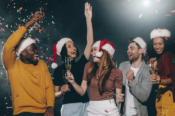 Canvas Print - People in Christmas hats dancing and throwing confetti while celebrating New Year in night club