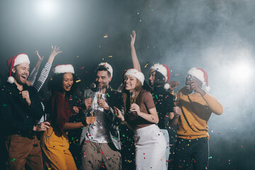 Wall Mural - Group of young people celebrating New Year in night club together while confetti flying around