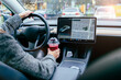 © Iryna - Rear view of unrecognizable female driving modern electric car. Tesla tablet screen.