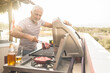 Mature man grilling steaks on a gas grill on his penthouse terrace