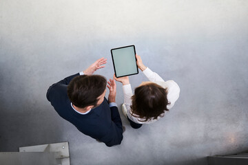 Wall Mural - Top view of businessman and woman with tablet talking in a factory