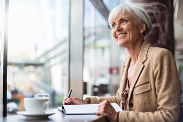 smiling senior businesswoman taking notes in a cafe