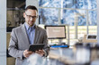 © tunedin - Businessman using tablet in a modern factory