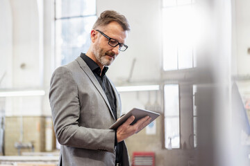 Wall Mural - Businessman using tablet in a factory