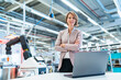 © tunedin - Portrait of confident businesswoman with laptop in a modern factory hall