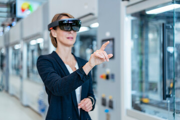 Canvas Print - Businesswoman wearing AR glasses in a modern factory