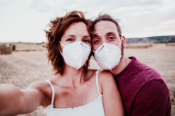 Wall Mural - Man and woman wearing face mask standing in field during COVID-19