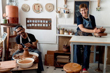 Smiling male and female potters working in workshop