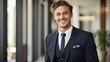 © Tom - Stylish young white businessman smiling, in a classic black suit, professional and approachable, indoor setting