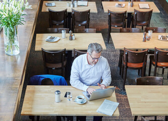 Wall Mural - Mature businessman in cafe using laptop