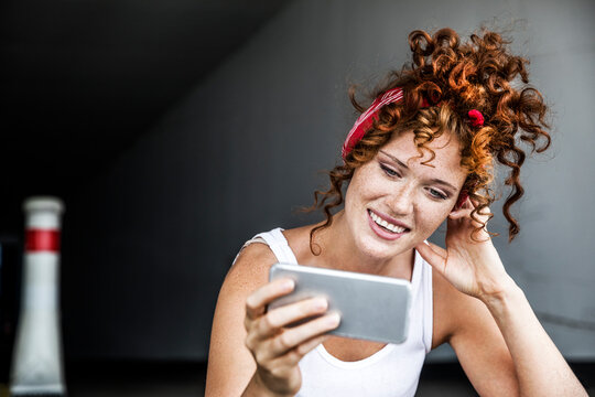 Smiling redheaded woman holding cell phone