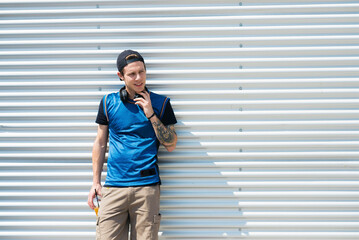 Wall Mural - Tattooed young man with headphones and soft drink watching something