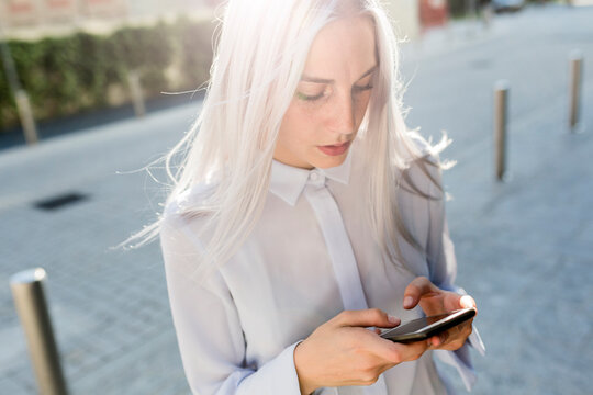 Young businesswoman checking cell phone in the city
