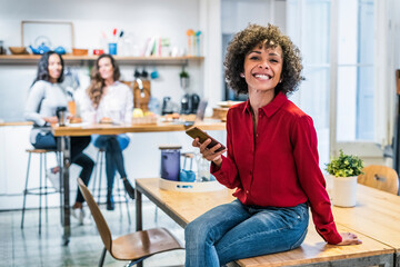 Wall Mural - Portrait of happy woman with cell phone sitting on table