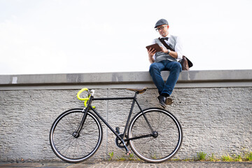 Wall Mural - Businessman with bicycle and tablet on a wall