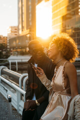 Wall Mural - Happy couple with cell phones in the city at sunset