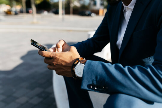 Close-upof businessman sitting outdoors using cell phone