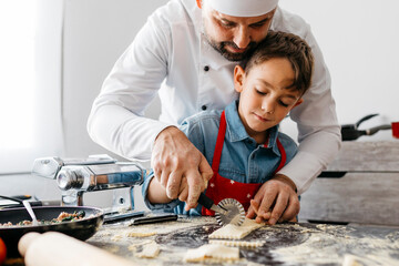 Father and son cutting homemade gluten free pasta with pasta cutter