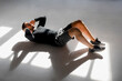 Athlete doing crunshes in sunlit studio