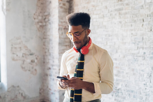 Stylish young man using smartphone in loft