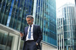 © tunedin - Businessman using mobile phone outside office building in city
