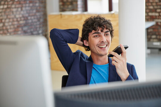 Young man working in office, leaving voice message