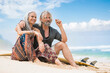 Portrait of senior hippie couple with surfboard relaxing on the beach