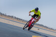 Determined cyclist riding bicycle on road against clear blue sky at desert in Dubai, United Arab Emirates