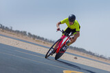 Fototapeta  - Determined cyclist riding bicycle on road against clear blue sky at desert in Dubai, United Arab Emirates