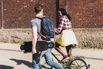 Poster - Young couple with bicycle and skateboard walking in the street