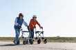 Two old friends wearing safety helmets, competing in a wheeled walker race