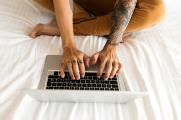 Wall Mural - Close-up of tattooed man using laptop in bed