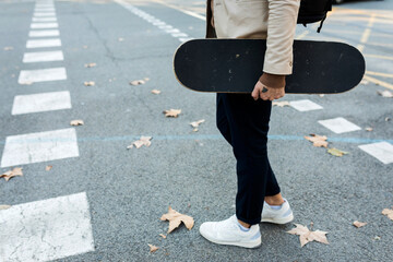 Sticker - Man with backpack and skateboard crossing the street in autumn, partial view