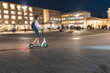 Young woman riding an electric scooter on 'Pariser Platz' at night, Berlin, Germany