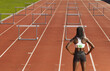 © Designpics - Back View of Woman Standing in Front of Hurdles on Track