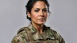 Stern Hispanic middle-aged female soldier in camouflage military uniform, serious expression, grey backdrop