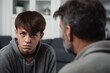 Close up caucasian man in front and upset guy behind sit at sofa to talk at home, offended teen son and middle aged father argument, adolescence problems, two generation conflict concept