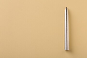 Wall Mural - One metal bullet on yellow background, top view. Space for text