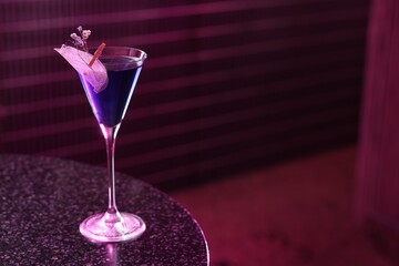 Wall Mural - Fresh alcoholic cocktail in glass on table against dark purple background. Space for text