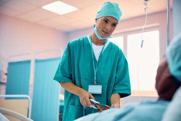 Wall Mural - Female doctor doctor putting pulse oximeter on black man's finger in hospital recovery unit.